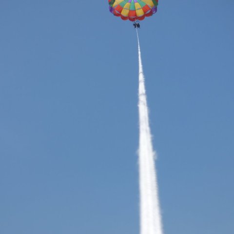 A rainbow parasail attached to the boat by a rope