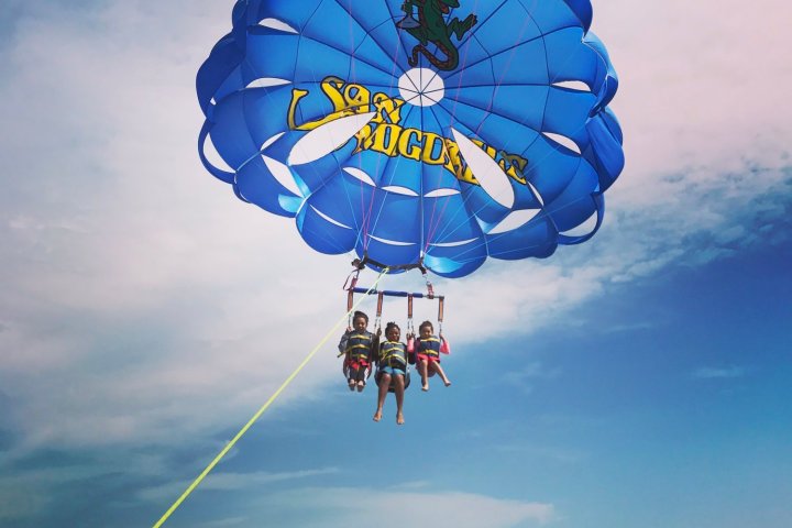 A family of three hanging in parasail harnesses