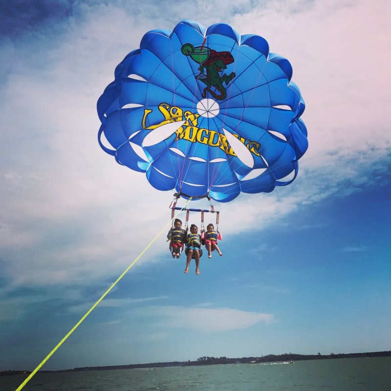 A family of three hanging in parasail harnesses