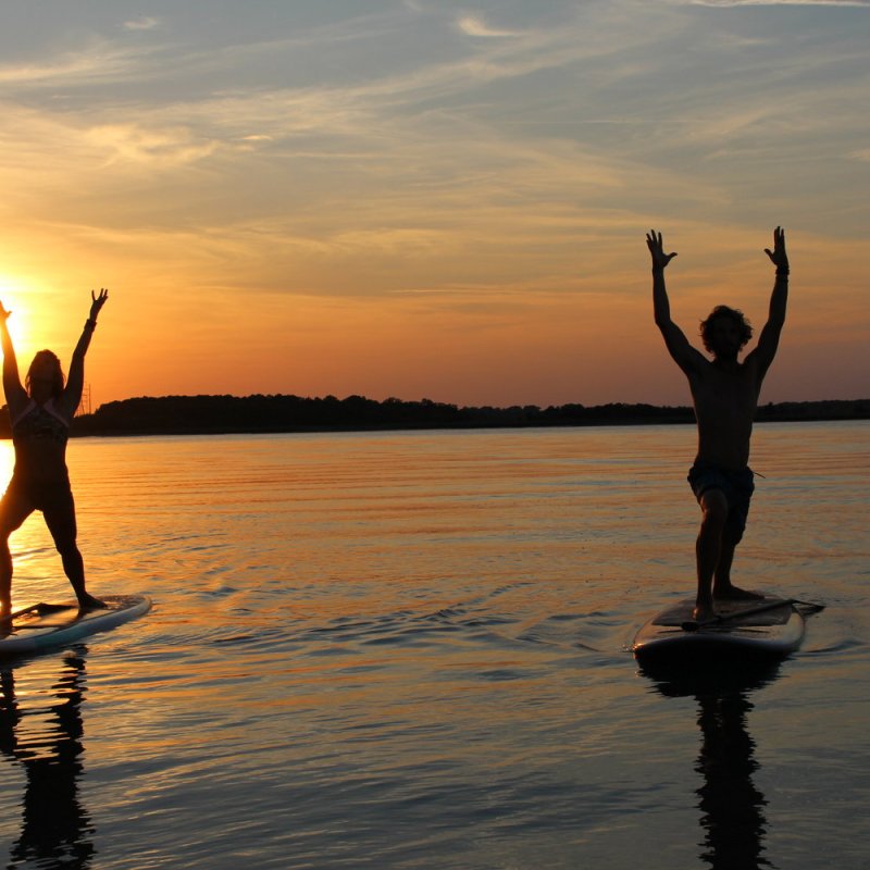 Warrior pose on paddle boards at sunset