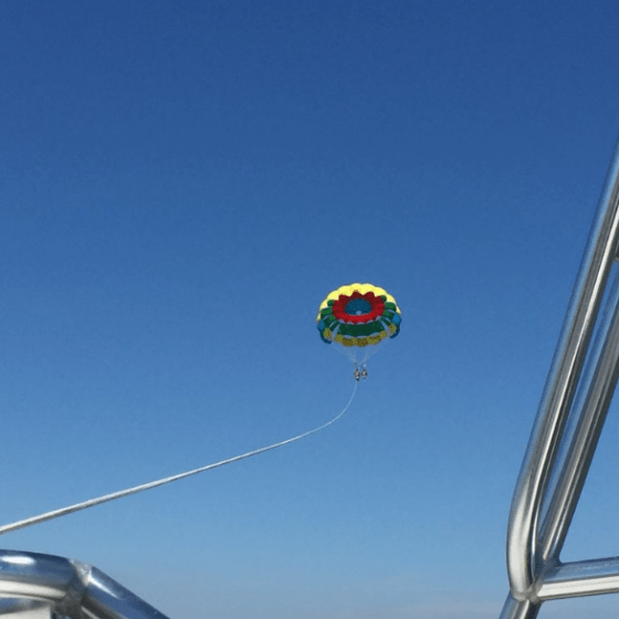 A rainbow parasail attached to the boat by a rope