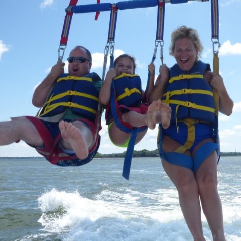 A family of three hanging in their parasail harnesses