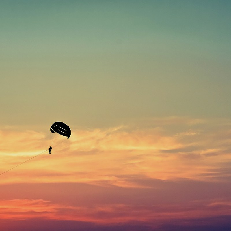 A parasail silhouette in front of a colorful sunset
