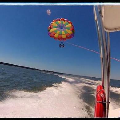 A rainbow parasail flying behind a boat