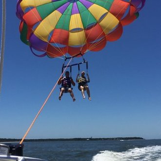 A rainbow parasail hovering over water behind a boat