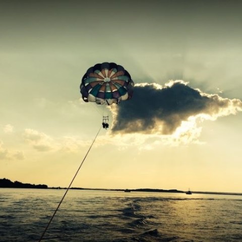 A rainbow parasail flying over wavy water