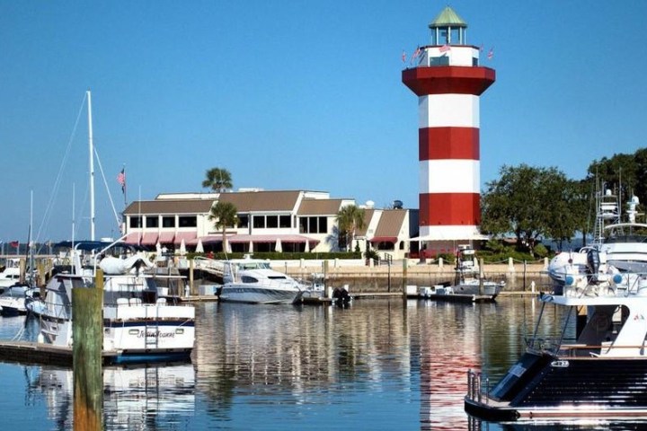 a boat is docked next to a body of water with Harbour Town Golf Links in the background