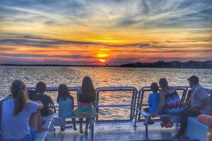 a group of people sitting on a bench next to a body of water
