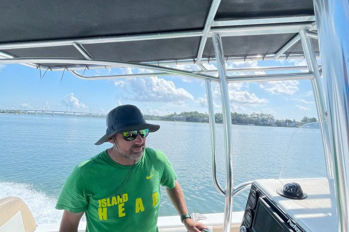a person standing in front of a boat next to a body of water