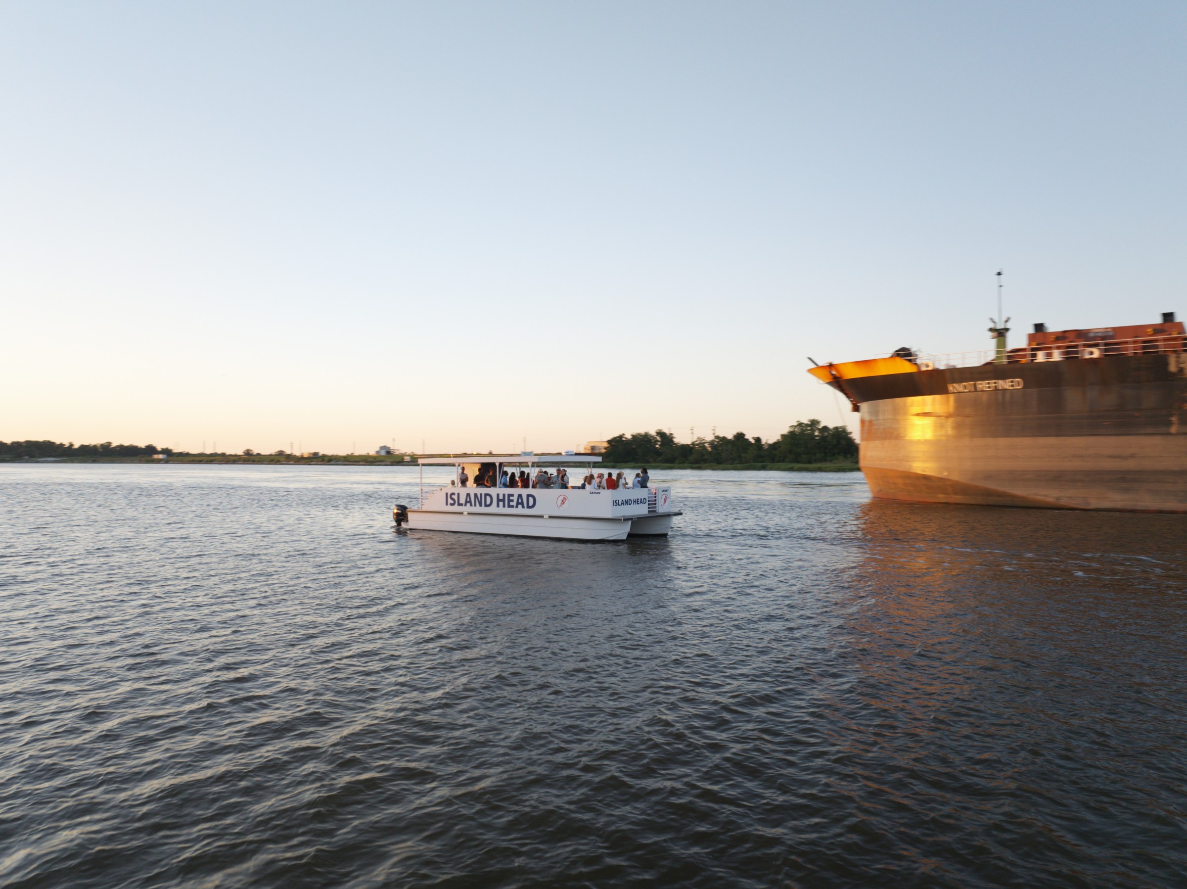 Small passenger boat near a large cargo ship on a wide river.
